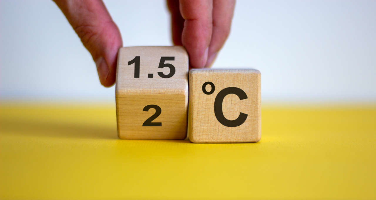 Symbol for limiting global warming. Male hand turnee a cube and changes the expression '2 C' to '1.5 C', or vice versa. 
